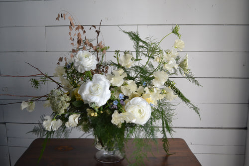 Floral arrangement in a vase on a wooden table with a white paneled background
