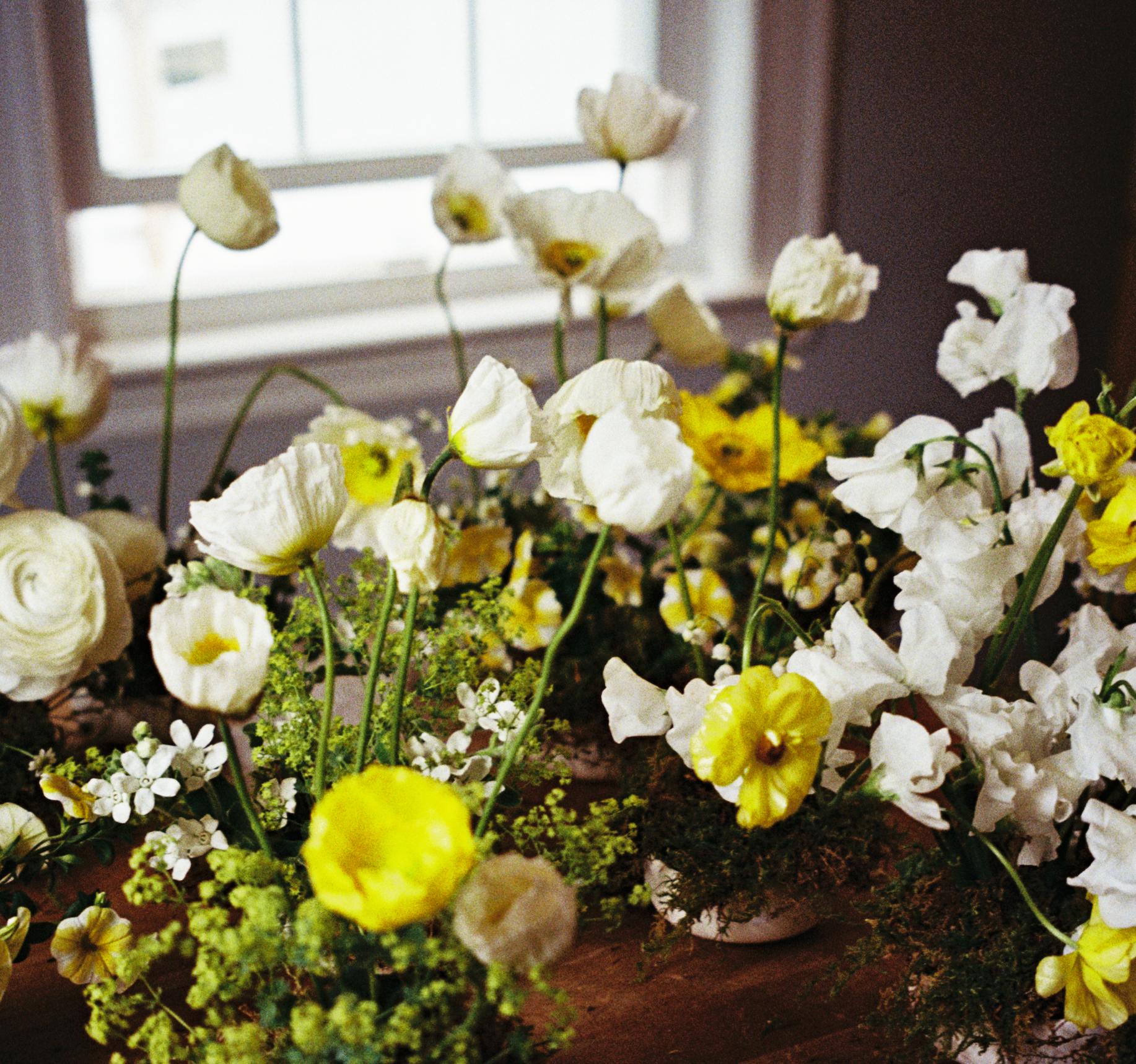 Floral arrangement with white and yellow flowers on a wooden surface.